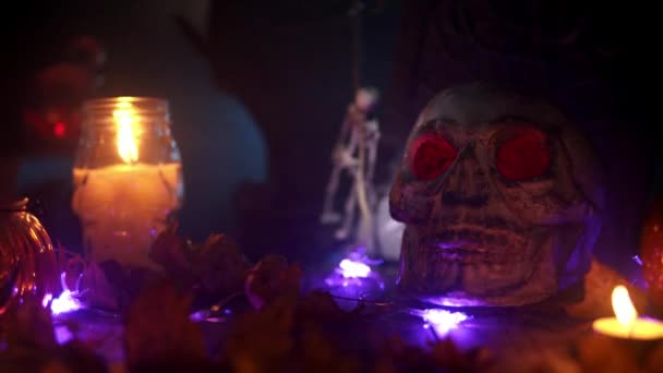 Spotlight schijnt op een schedel met gloeiende ogen in het kaarslicht instelling voor de dag van de doden — Stockvideo