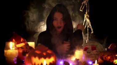 Siyah mantolu genç kız sigara içiyor ve balkabaklarının arasında gülümsüyor.