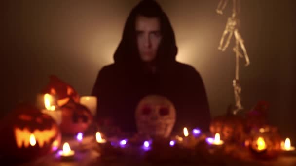 Muž v černém plášti a kapuci se dívá přímo do kamery na Halloween — Stock video