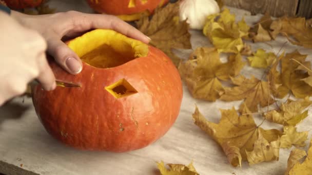 Lámpást csinálni Halloweenkor egy tökből, aki késsel vágja ki a szemét. — Stock videók