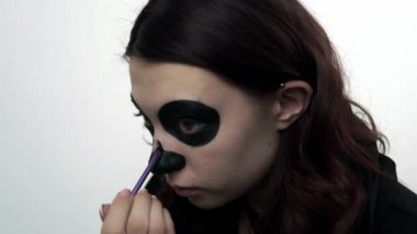 Santa Muerte bayramı makyajı için burnunu siyaha boyuyor.