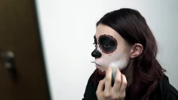 Κορίτσι ζωγραφίζει το πρόσωπό της λευκό ένα παραδοσιακό μακιγιάζ για τις διακοπές της Santa Muerte — Αρχείο Βίντεο