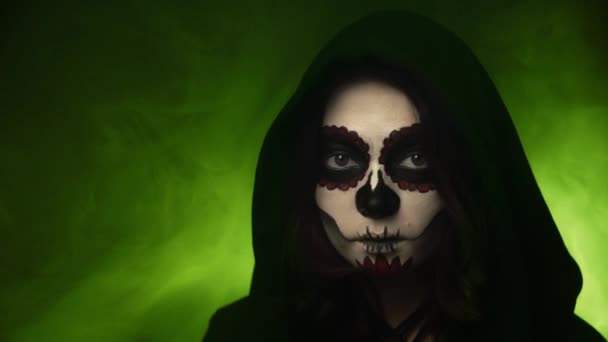 Bruja con esqueleto maquillaje sonríe sobre un fondo de humo — Vídeos de Stock