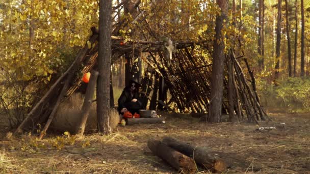 Heks in een woud hut gemaakt van bomen oefent voodoo magie — Stockvideo