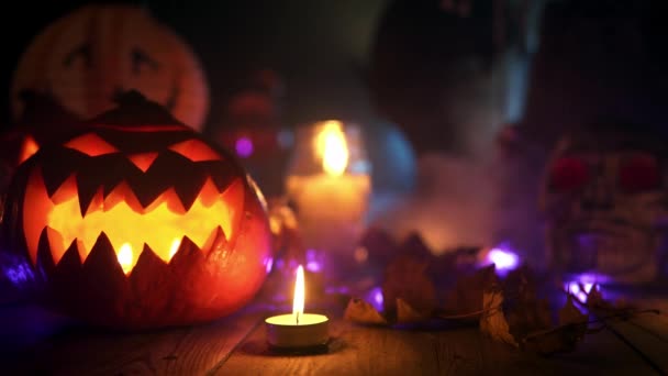 Halloween-Kürbis steht am Holztisch neben brennender Kerze — Stockvideo