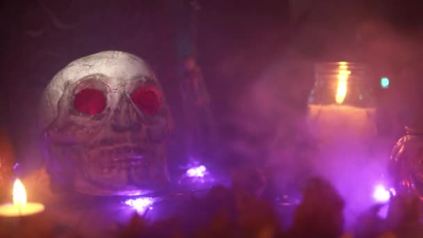 煙によって吹き飛ばされているハロウィーンの頭蓋骨の上を光のビームが歩いています。 — ストック動画