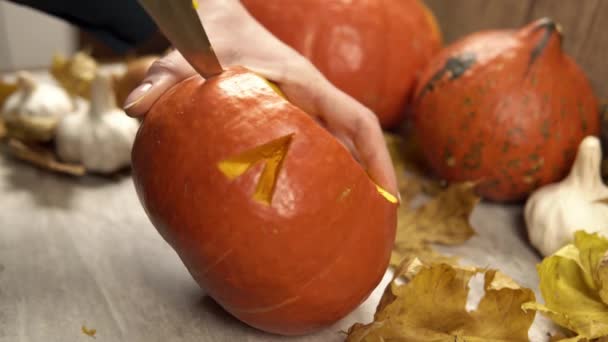 Vrouw gebruikt scherp mes om ogen te snijden bij de diy halloween jack-o-lantaarn — Stockvideo