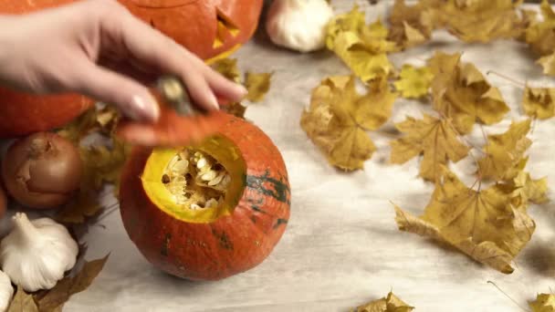 Het meisje neemt het deksel van gesneden pompoen dat aan de houten tafel staat weg. — Stockvideo