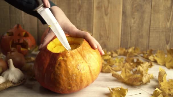 Dívka dělá řezy uvnitř halloween dýně pomocí ostrého nože — Stock video