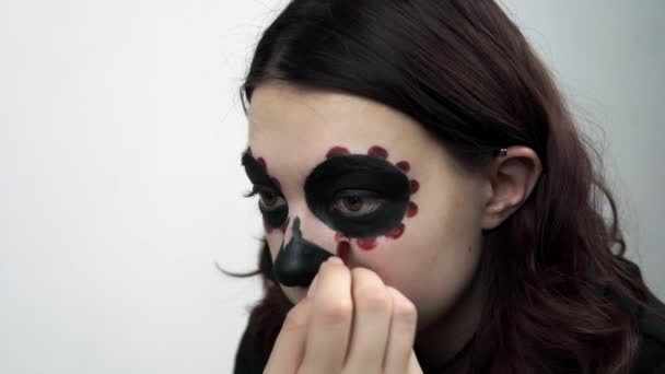 Žena používá červenou tužku nakreslit malé detaily pro její Santa Muerte make-up — Stock video