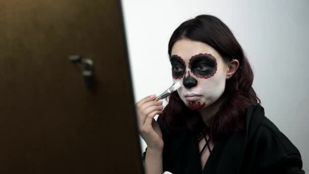 Mulher aplica tinta branca do bodyart em seu rosto para maquiagem santa muerte — Vídeo de Stock
