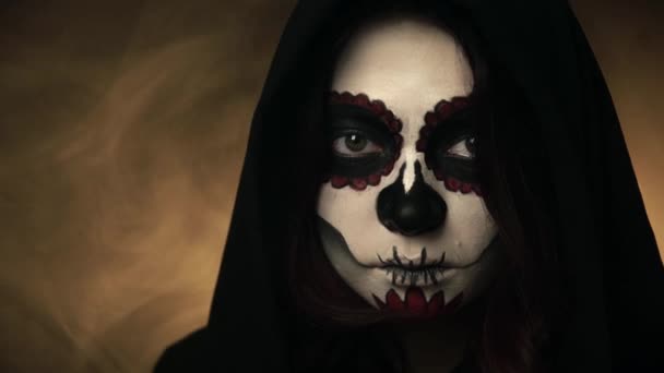 Woman in black hood and santa muerte makeup calmly watches straight — Stock Video