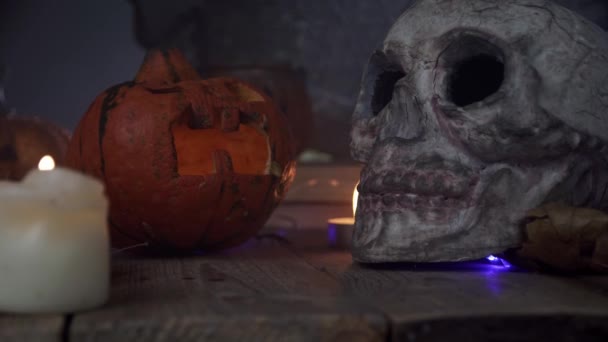 Gruselige Halloween-Kürbisse, Totenkopf und Grabsteine stehen am Tisch — Stockvideo