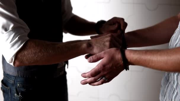 A férfi leveszi a bilincset egy másik férfi kezéről. — Stock videók