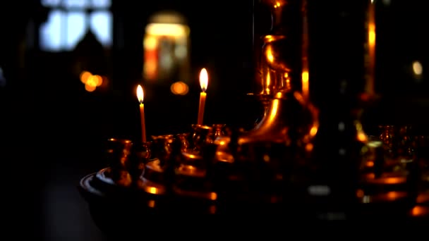 东正教教堂黑暗房间里的一个大金烛台上燃着两支蜡烛 — 图库视频影像