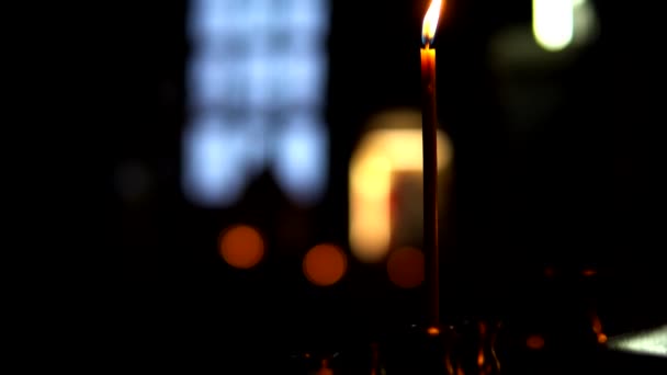 Une bougie allumée dans la pièce sombre de l'église orthodoxe, caméra panoramique vers le haut — Video