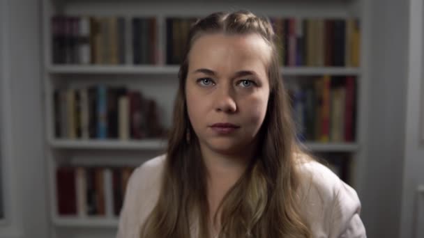 Vrouwenpsycholoog knikt en stemt in met portret tegen achtergrond van boeken — Stockvideo