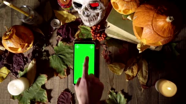 Usando un teléfono con una pantalla verde en el fondo de las decoraciones de Halloween — Vídeos de Stock