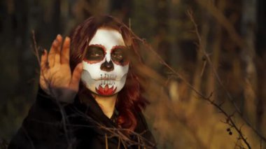 Noel Baba makyajlı cadı dallara bakıyor ve onlara dokunuyor.