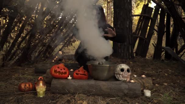 Bruxa de manto preto e maquiagem de crânio de açúcar move as mãos sobre a fumaça — Vídeo de Stock