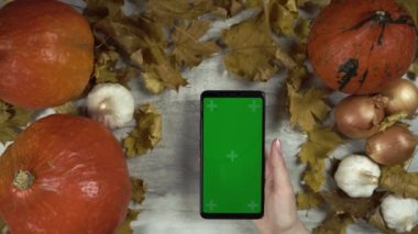 Kadın yeşil ekranlı akıllı telefonu hareket ettiriyor ve sol eliyle ona dokunuyor.