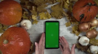 Kadın akıllı telefonu balkabaklarının arasına koyar ve alıp götürür.