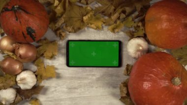 Akıllı telefon masada uzanıyor ve kadın vuruşları, paket jesti yeşil ekran