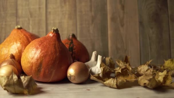 Trockene Blätter fallen auf den Tisch, auf dem Kürbisse und Zwiebeln mit Knoblauch stehen — Stockvideo
