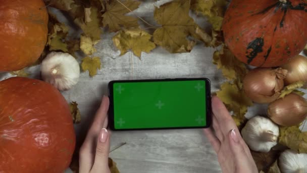 Woman with french manicure puts smartphone with green screen at the table — Stock Video