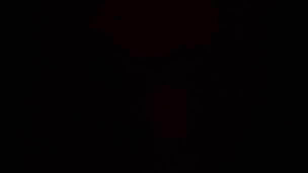 주황 빛이 까만 배경을 비추며 번쩍 이는 동안 회전 한다 — 비디오