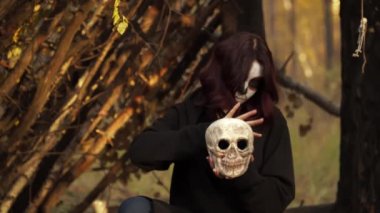 Noel Baba makyajlı cadı kafatasını tutuyor ve elini etrafında gezdiriyor.