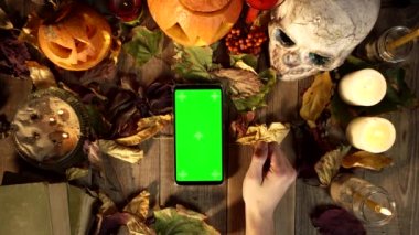 Cadılar Bayramı dekorasyonunun arka planında dikey akıllı telefon kullanmak için jestler