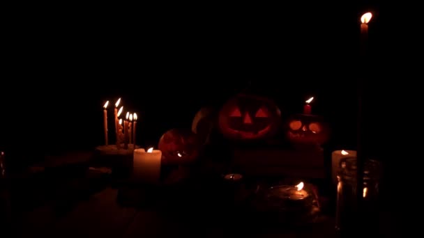 Jack pumpkins surrounded by candles in slow motion on a dark background — Stock Video