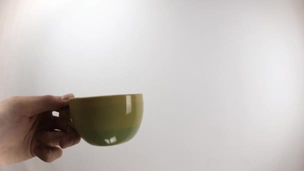 Brazo masculino sostiene la taza verde con bebida y la está bebiendo — Vídeo de stock
