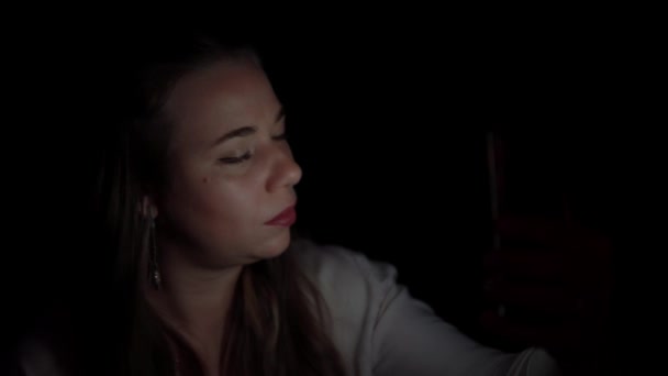 Жінка намагається зробити селфі зі своїм телефоном в студії з темрявою — стокове відео