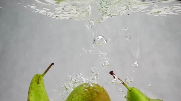 Las peras caen al agua con salpicaduras y burbujas en cámara lenta. — Vídeos de Stock