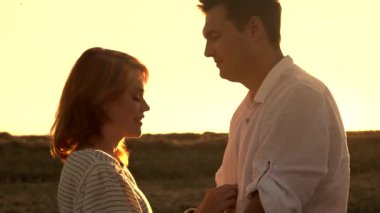 Mutlu beyaz çift günbatımında bir tarlada duruyor.