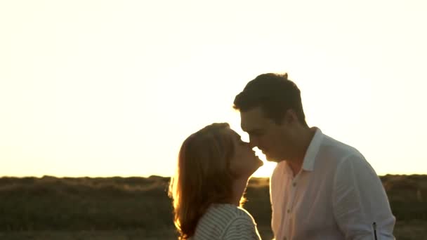 Casal caucasiano está se beijando no pôr do sol horizonte de fundo em pé no campo em câmera lenta — Vídeo de Stock