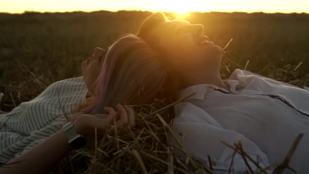 Egy férfi és egy nő lassú mozgása, akik a szénakazalban fekszenek és beszélgetnek naplementekor. — Stock videók