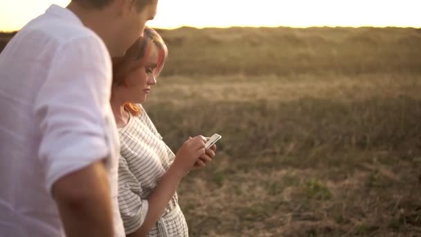 Jong Kaukasisch echtpaar dat in een zomerveld staat te kijken naar een mobiele telefoon in Slowmo — Stockvideo