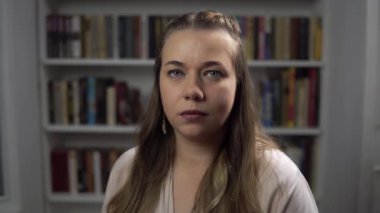 Kitap raflarının arkasında gülümseyen orta yaşlı bir kadının portresi