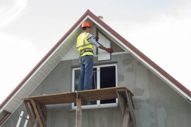 İnşaat işçisi bir recessed çatı saçak bağlar.