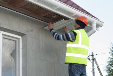 İnşaat işçisi bir recessed çatı saçak bağlar.