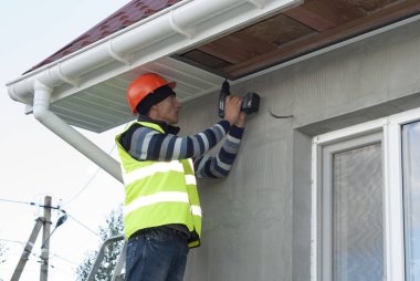 İnşaat işçisi bir recessed çatı saçak bağlar.