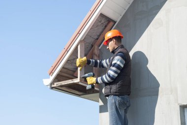 İnşaat işçisi bir recessed çatı saçak bağlar.