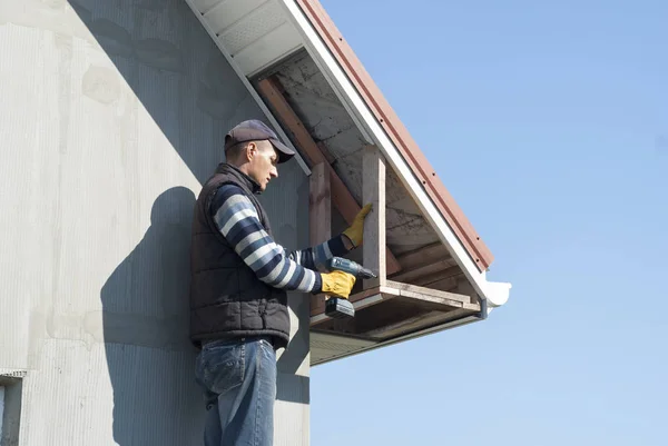建設労働者は屋根庇の軒裏をマウントします — ストック写真