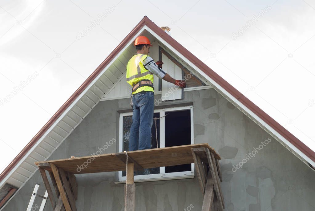 construction worker mounts a soffit on the roof eaves