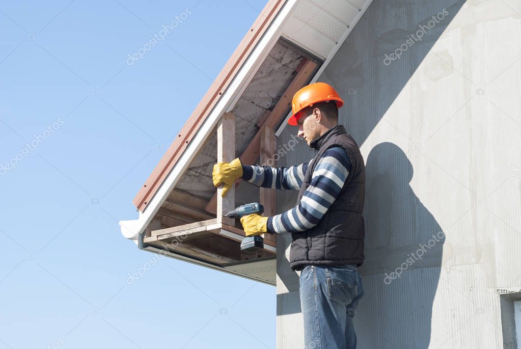 construction worker mounts a soffit on the roof eaves