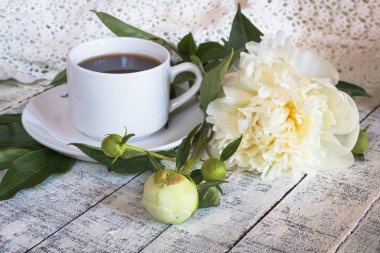 Beyaz ahşap masada kahve ve güzel beyaz şakayık sabah fincan