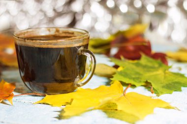 Sabah sonbahar yaprakları bir masada bir fincan